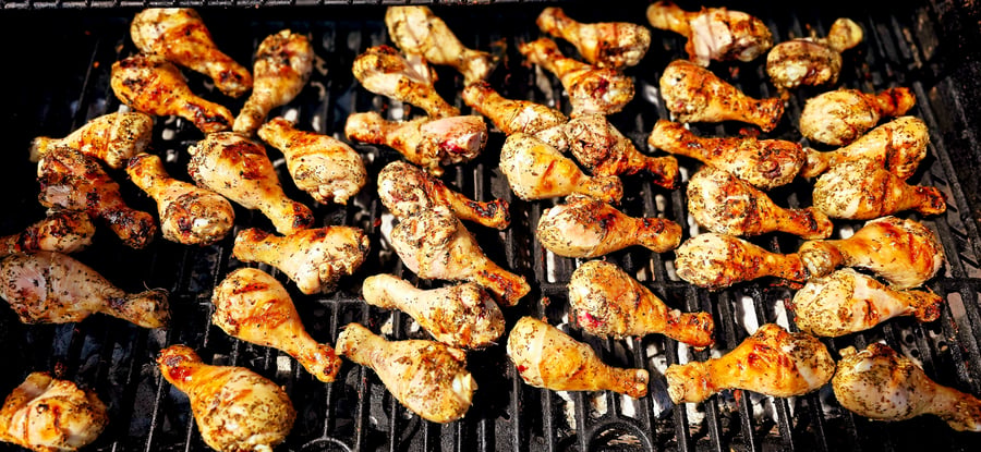 Delicious seasoned chicken drumsticks cooking on a hot grill, perfect for a summer BBQ event