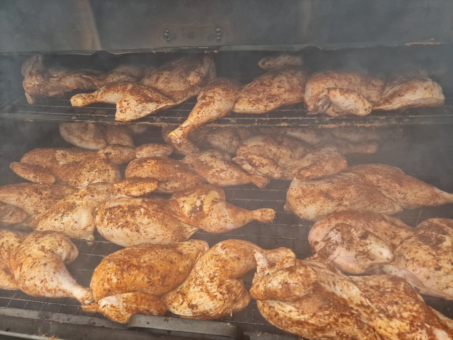Seasoned chicken portions cooking on a grill, with smoke rising, ready for a delicious BBQ feast