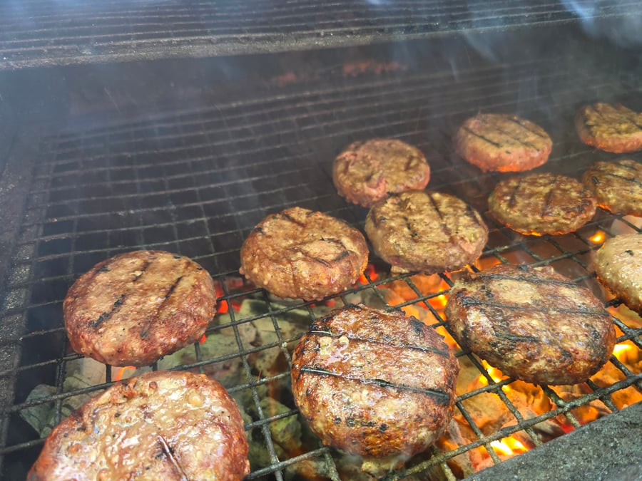 Juicy burgers sizzling on the grill over hot coals, perfect for any outdoor event or casual gathering