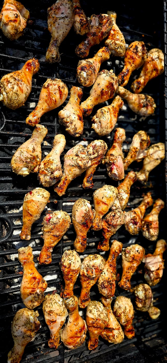Deliciously seasoned chicken drumsticks cooking on a BBQ grill, perfect for any outdoor event