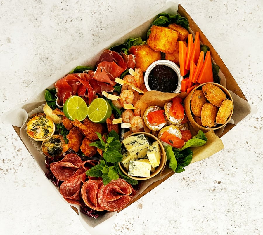 A beautifully arranged buffet box featuring cured meats, cheeses, seafood, and mini quiches, perfect for any event