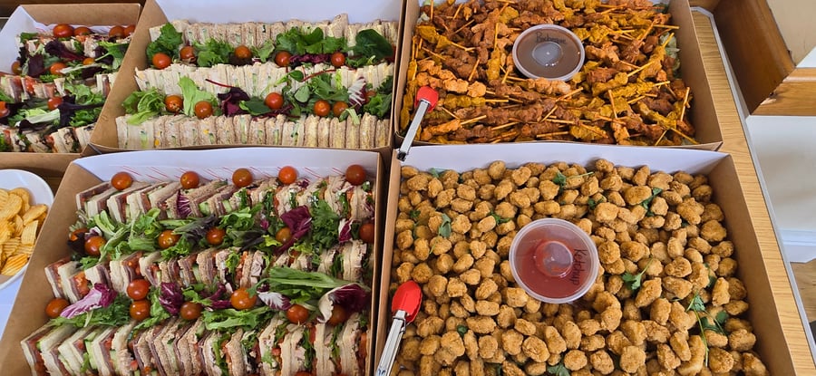 A vibrant buffet spread featuring neatly arranged sandwiches, chicken satay skewers, and crispy popcorn chicken, perfect for any event