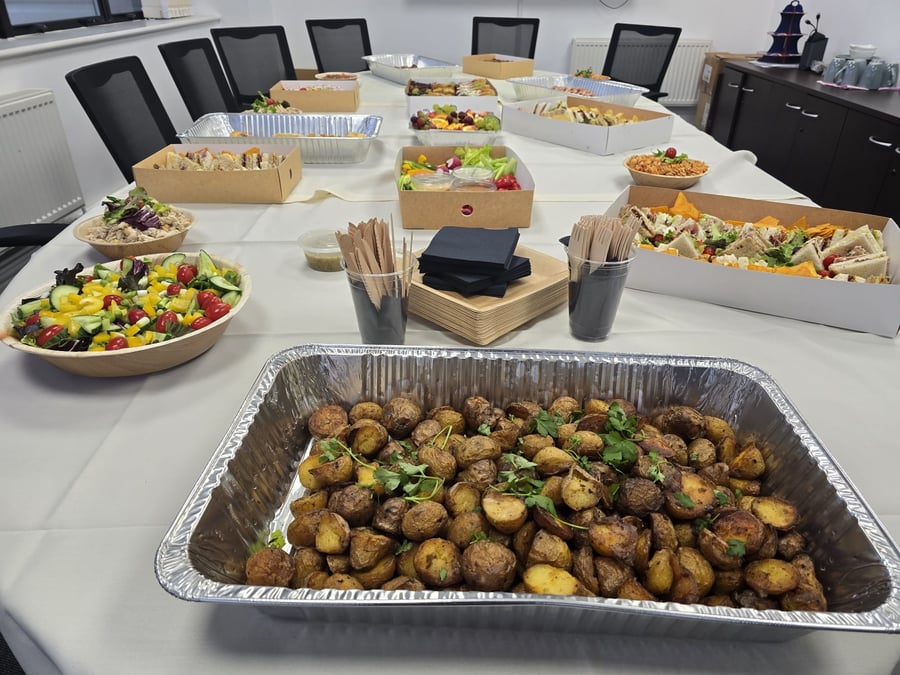 A corporate buffet spread featuring roasted potatoes, fresh salads, and assorted sandwiches, perfect for a business lunch