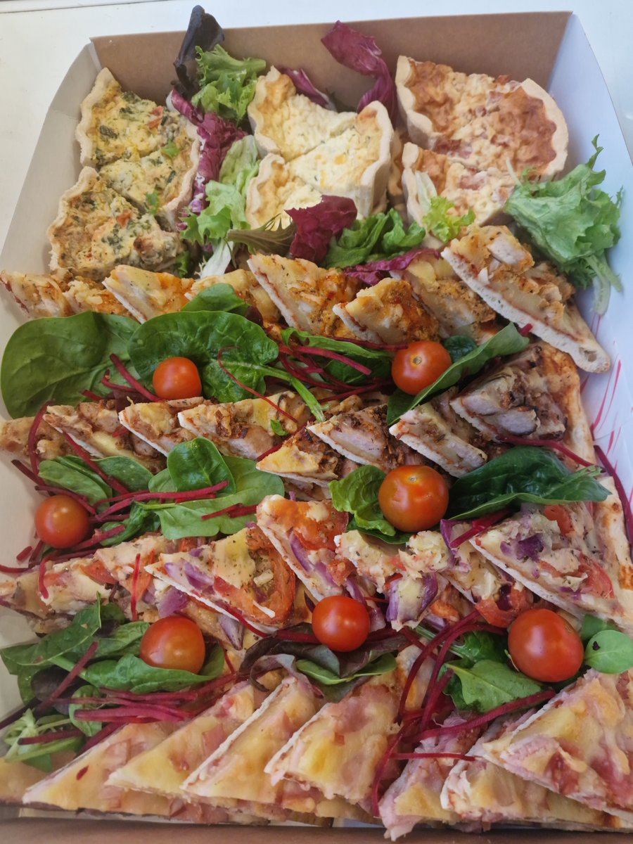 A vibrant selection of freshly prepared quiches and flatbreads, garnished with mixed leaves and cherry tomatoes, perfect for any event