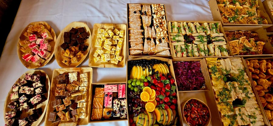 An overhead view of a large buffet spread featuring sandwiches, cakes, fruit, and other savoury dishes, all beautifully arranged for an