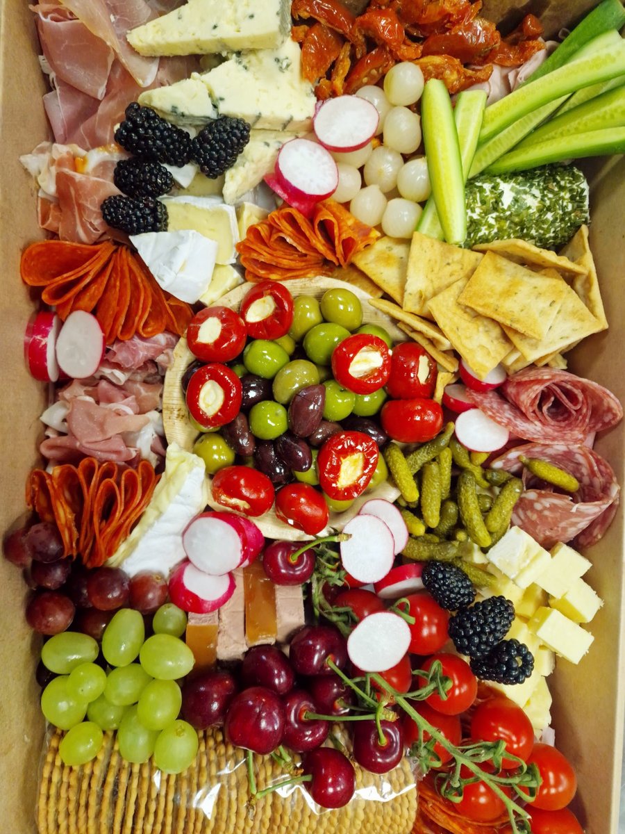 A vibrant buffet platter featuring cheeses, cured meats, fresh fruit, vegetables, and crackers, perfect for any event