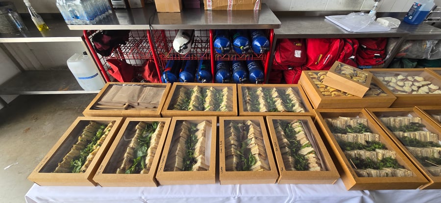 A selection of freshly prepared sandwiches and pastries in individual boxes, ready for delivery to a welfare catering event