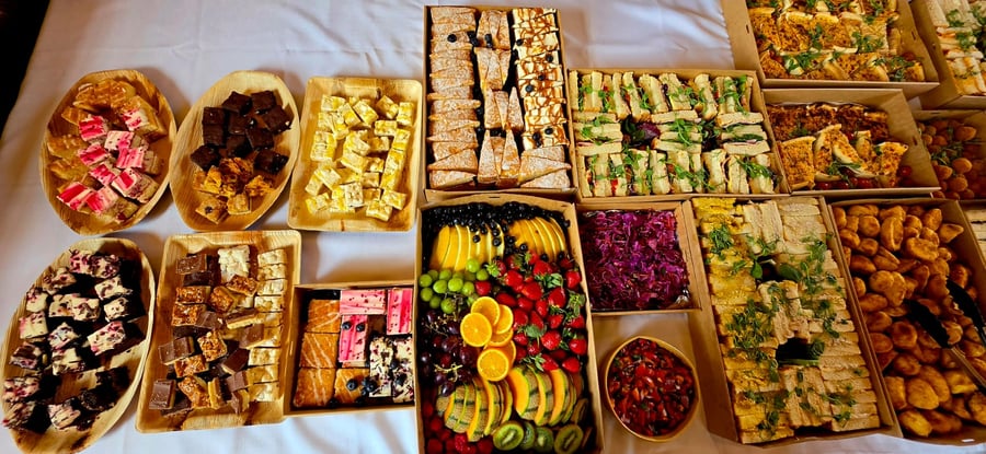 An overhead shot of a buffet spread featuring sandwiches, fruit platters, and various sweet treats, perfect for any event