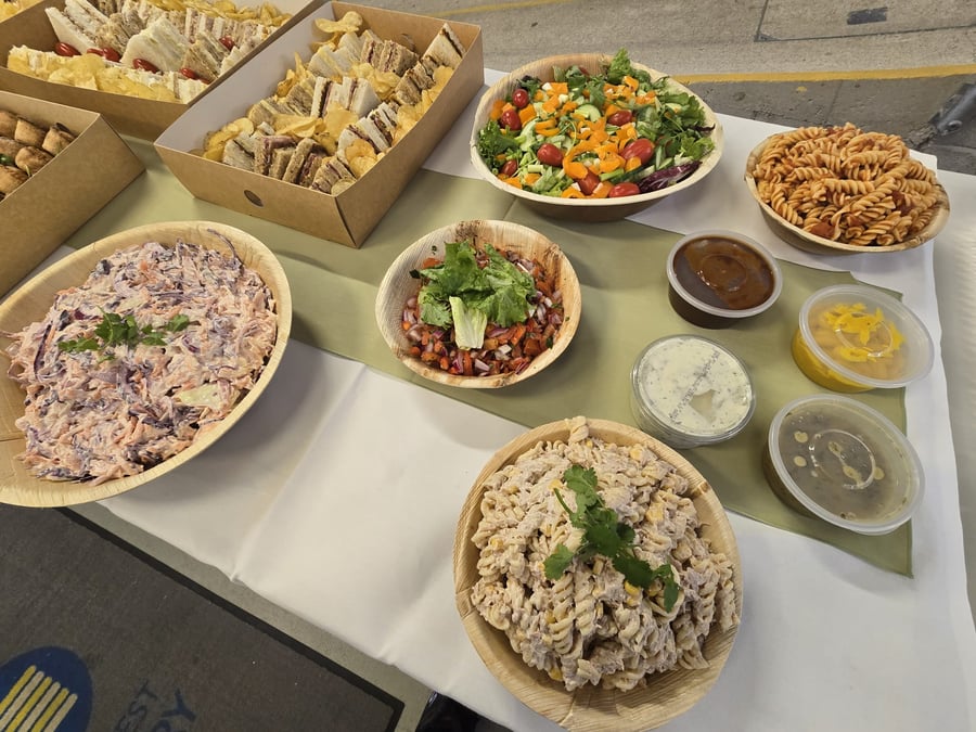 A vibrant buffet spread featuring sandwiches, pasta salads, coleslaw, and fresh green salad, perfect for any event