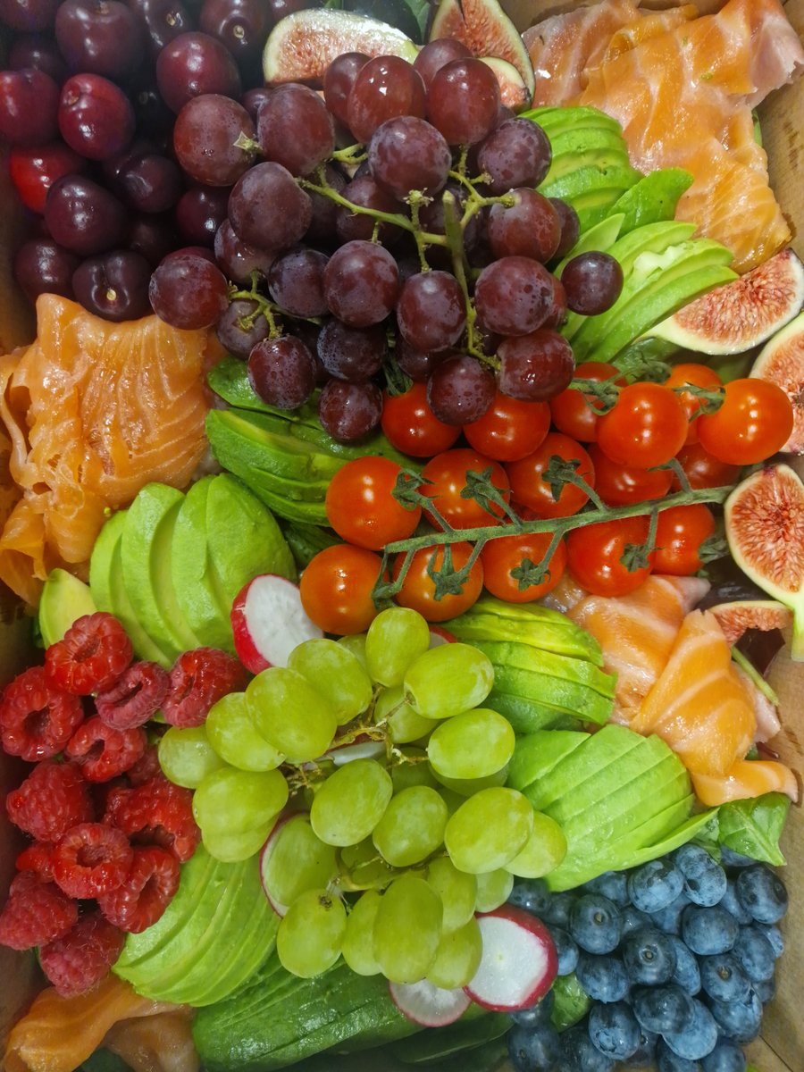 A vibrant buffet platter featuring smoked salmon, fresh avocado, cherry tomatoes, figs, radishes, and a variety of grapes and berries (2)