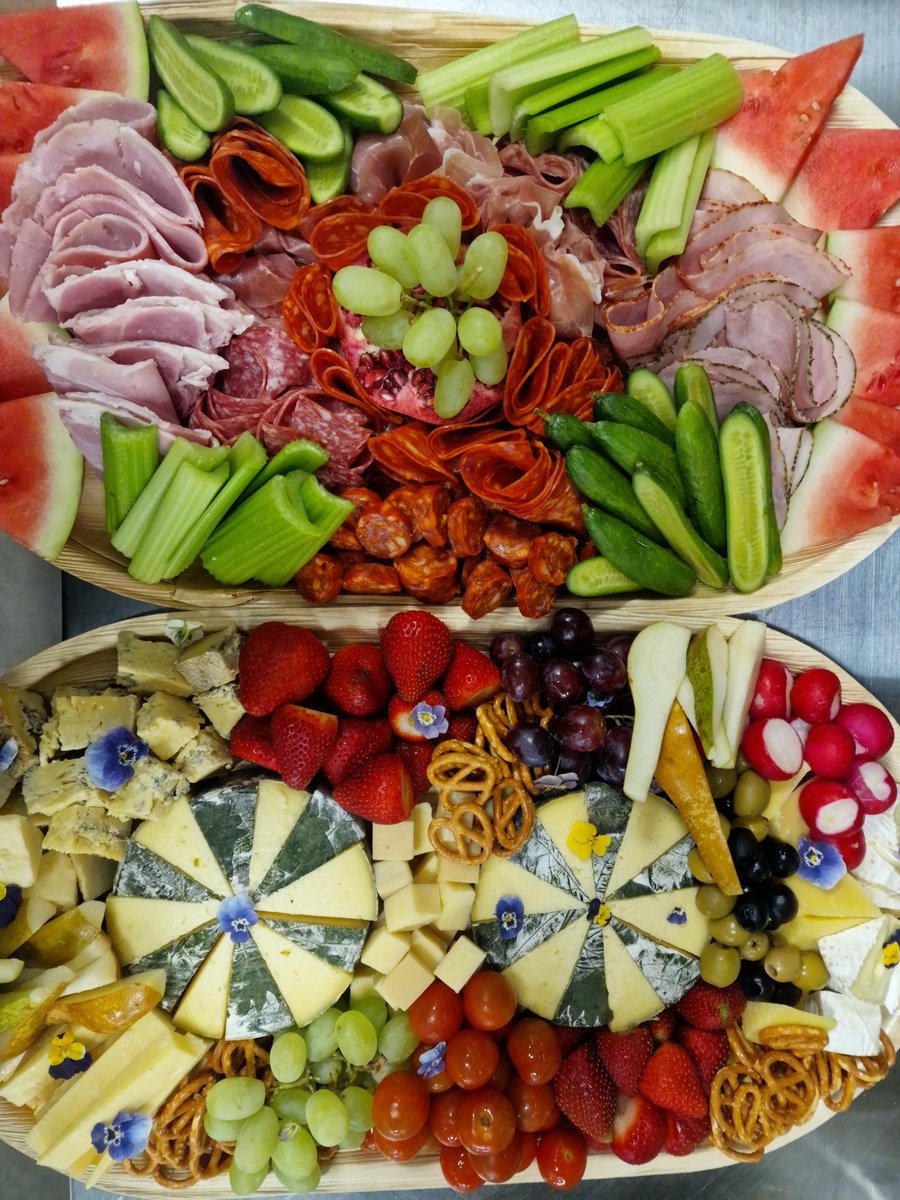 Two beautifully arranged platters featuring a selection of cured meats, cheeses, fresh fruit, and vegetables, perfect for any event