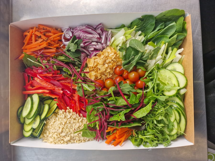 A vibrant selection of fresh salad ingredients, including carrots, red onion, peppers, cucumber, and cherry tomatoes, arranged in a