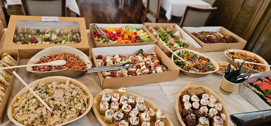 A vibrant buffet spread featuring sandwiches, salads, charcuterie skewers, and mini cupcakes, perfect for any event
