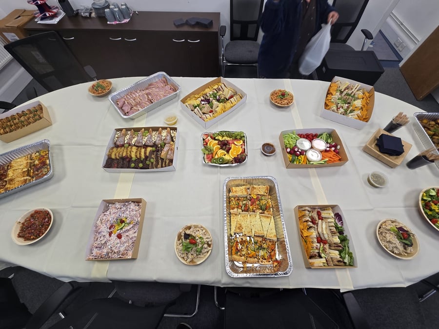 A wide selection of buffet dishes, including sandwiches, salads, and fruit platters, laid out on a table for an event