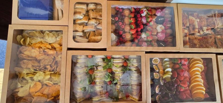 A selection of buffet boxes featuring crisps, sausage rolls, sandwiches, fruit, and sweet treats, ideal for film and TV crew catering