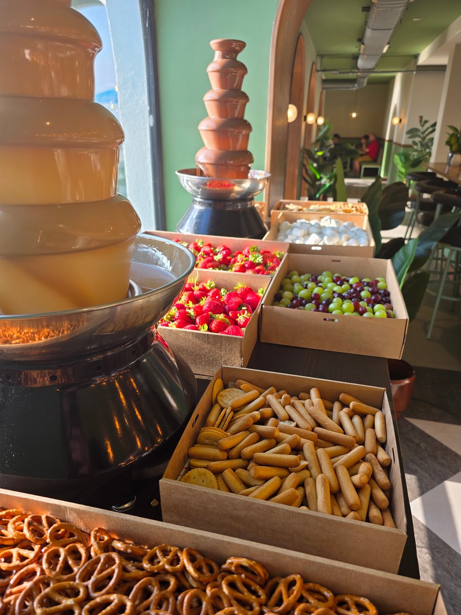 A delightful chocolate fountain with fresh strawberries, grapes, marshmallows, pretzels, and breadsticks for dipping