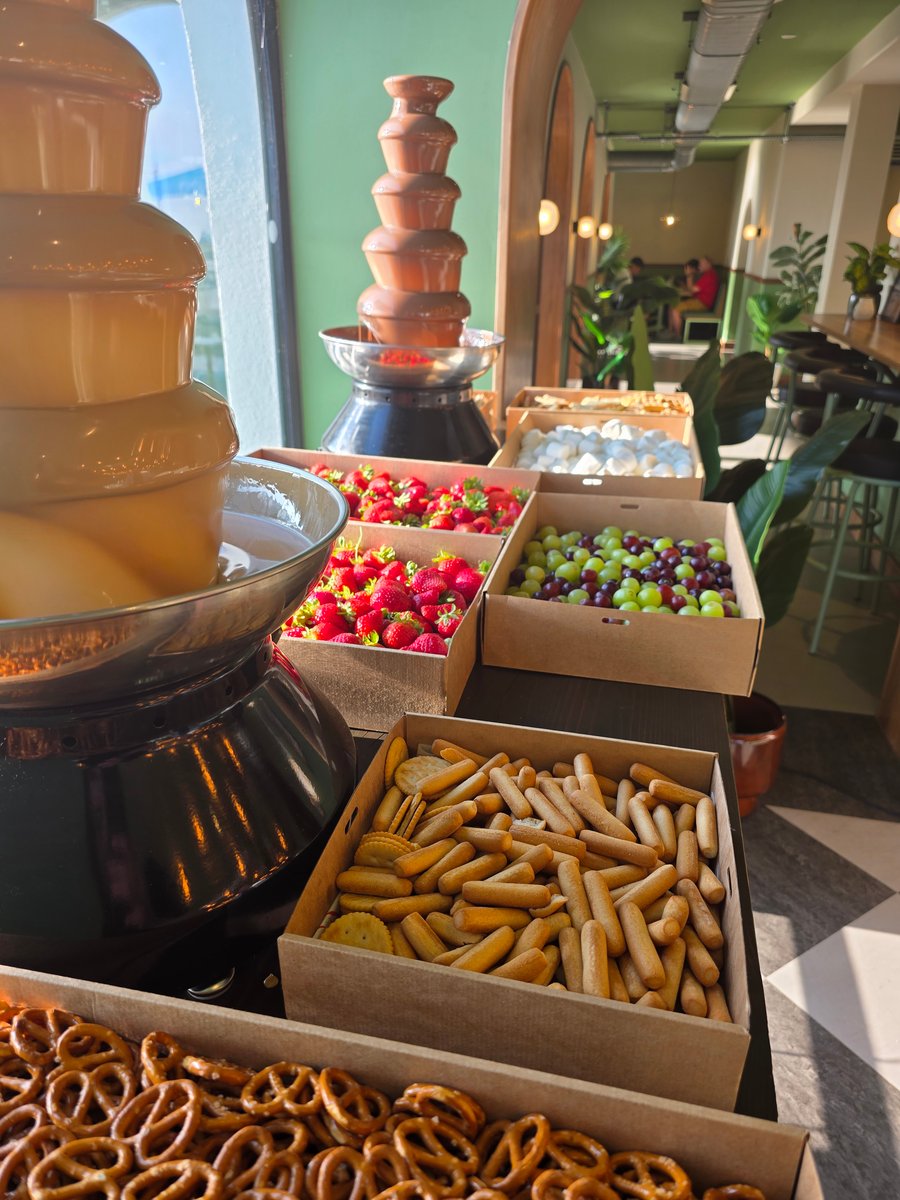 A delightful chocolate fountain display with fresh strawberries, grapes, marshmallows, and various biscuits for dipping