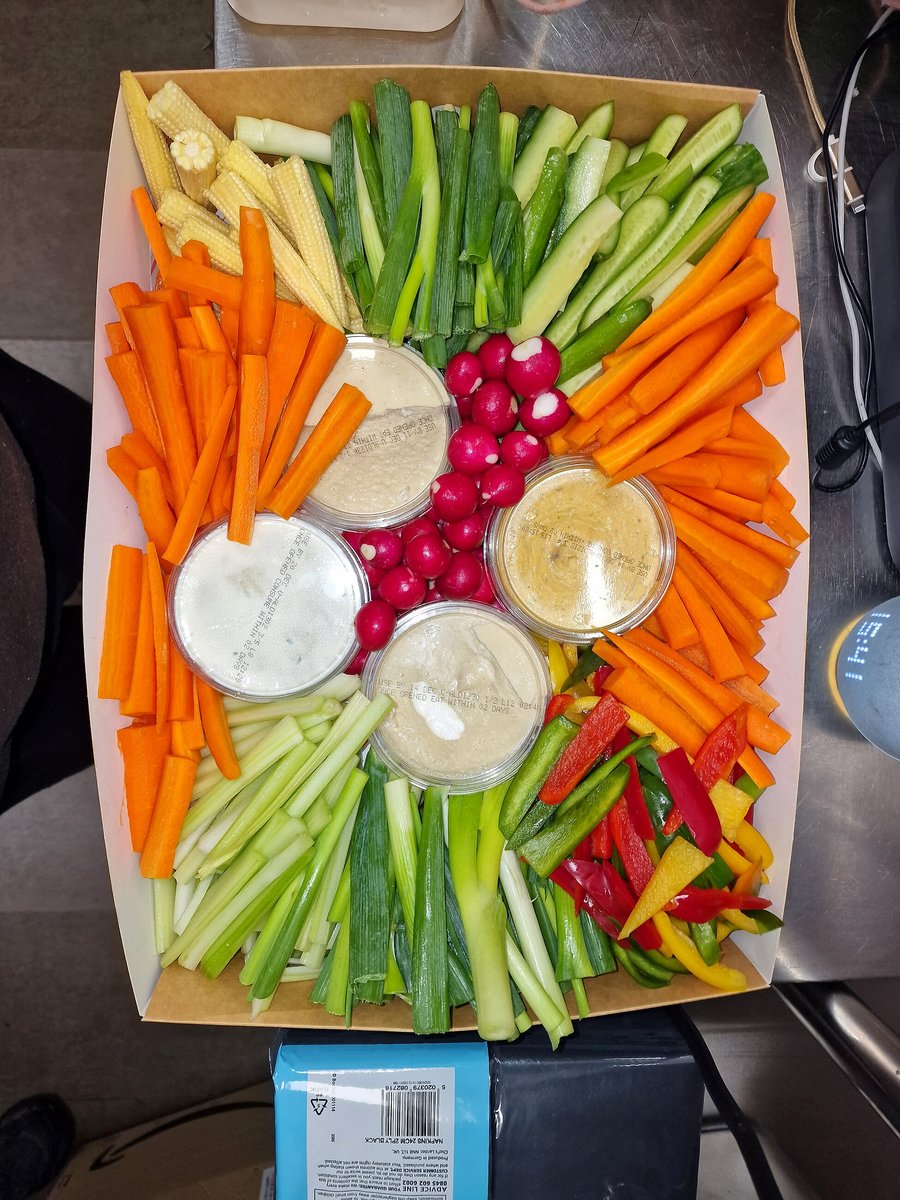 A vibrant platter of fresh crudités and dips arranged in a catering box