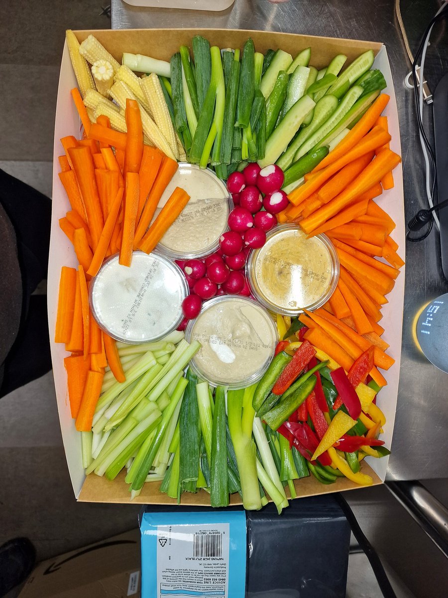 A platter of fresh, colorful crudités with various dips is neatly arranged