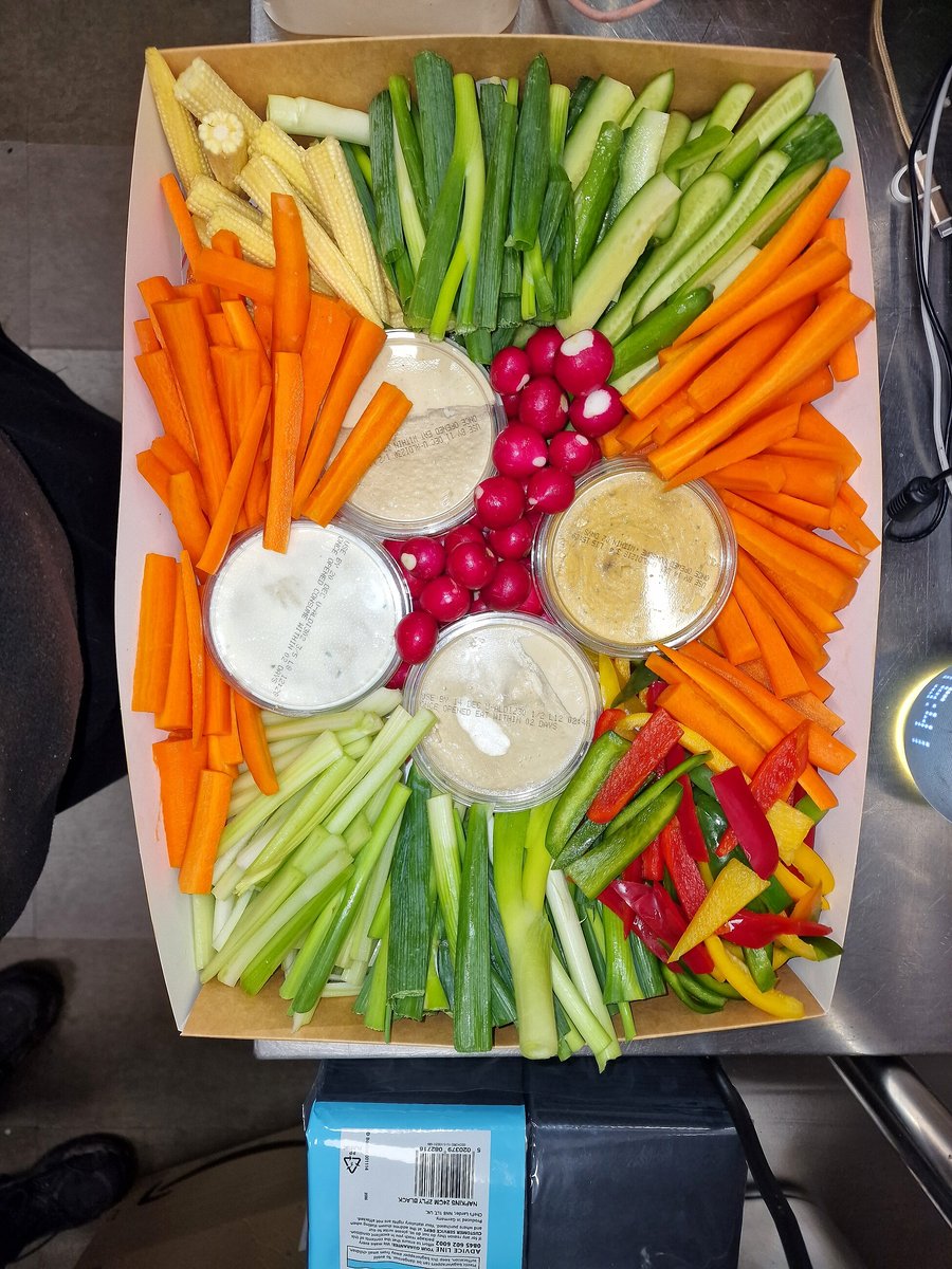 A large platter of fresh, colorful crudités with dips, ready for an event
