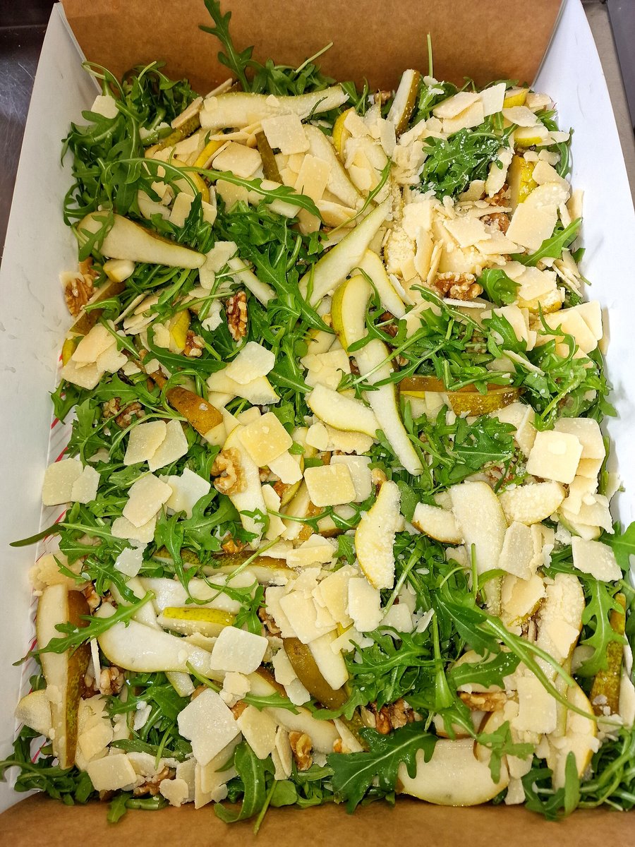 A fresh salad with pear, walnuts, and parmesan cheese in a box