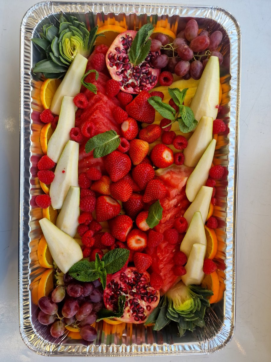 A large catering platter filled with a vibrant assortment of fresh fruits and garnishes