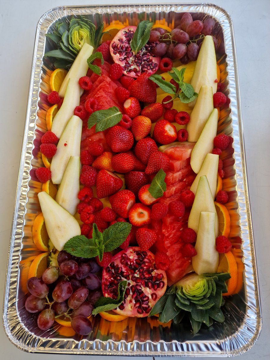 A large, vibrant platter overflowing with fresh strawberries, raspberries, grapes, watermelon, and pomegranate