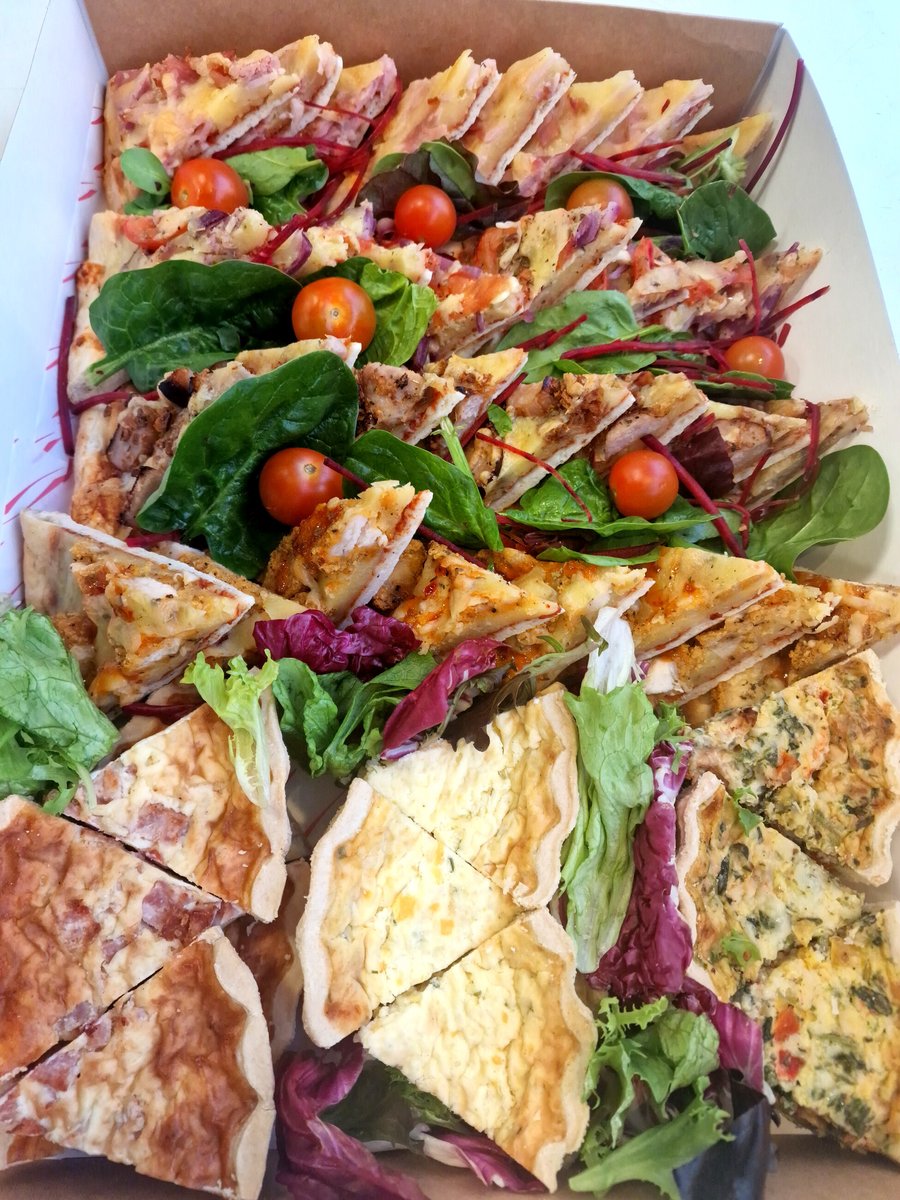 A catering box filled with assorted quiches, tarts, and fresh salad garnishes (2)