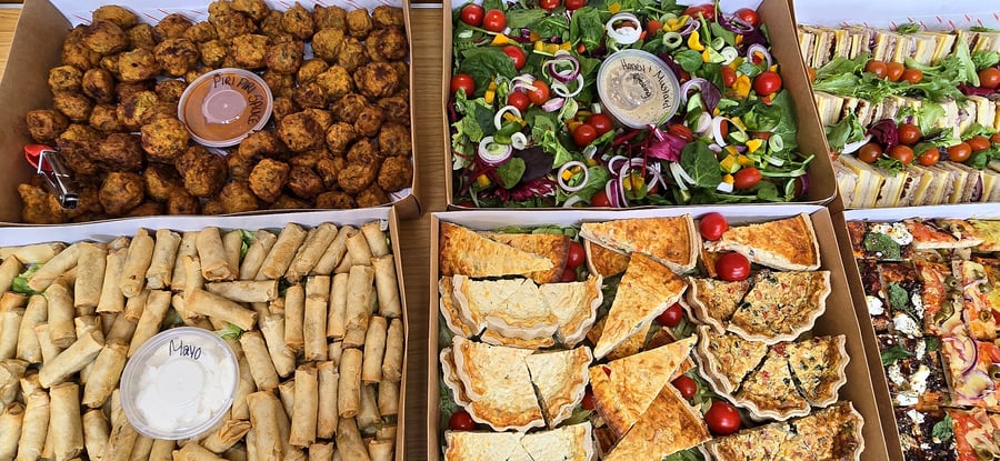 A variety of catering platters including sandwiches, salad, quiches, and finger foods