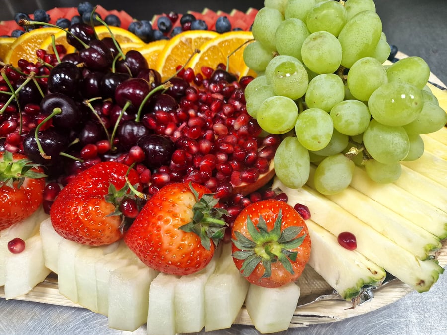 A vibrant platter overflowing with fresh strawberries, grapes, cherries, pomegranate, and pineapple