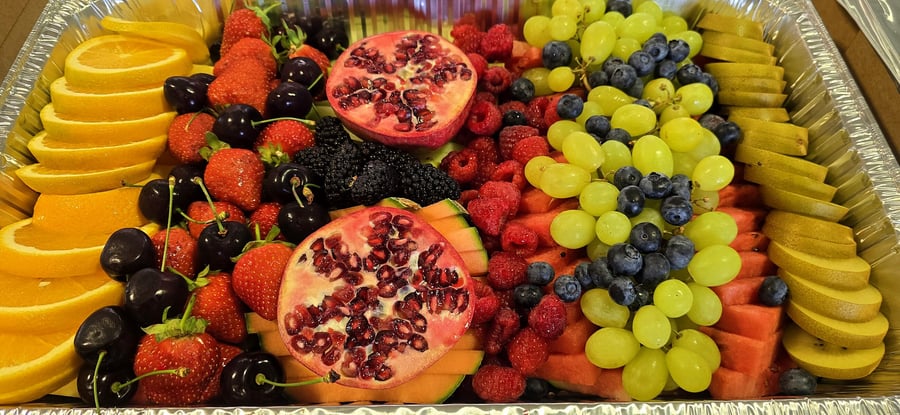 A vibrant and abundant platter of fresh fruits, including berries, grapes, and oranges