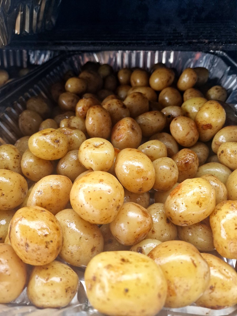 Close-up of freshly cooked new potatoes in a foil tray, likely from a BBQ