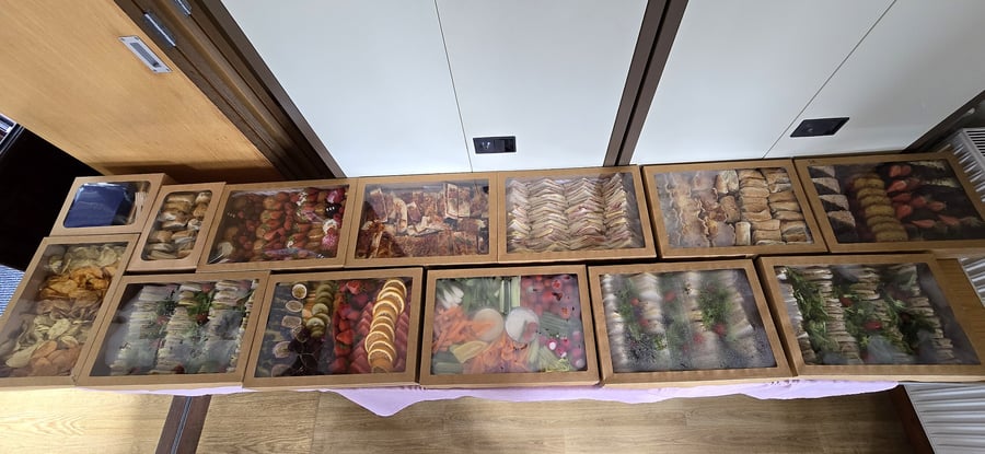A long table laden with an assortment of catering boxes filled with food