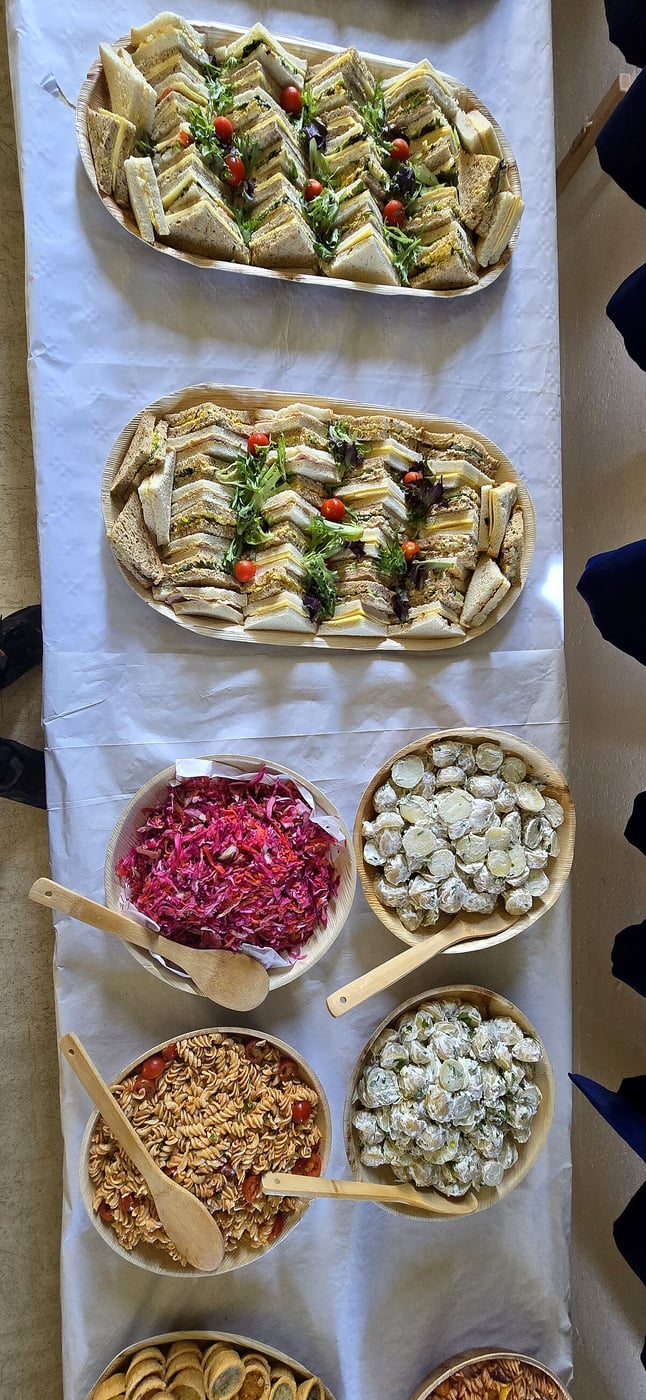 Platters of assorted sandwiches and bowls of salads laid out on a table