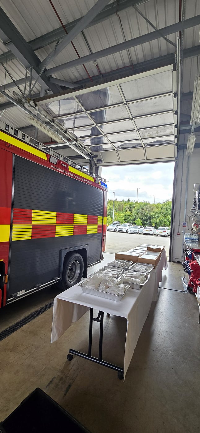 Catering setup with food trays next to a fire engine inside a station