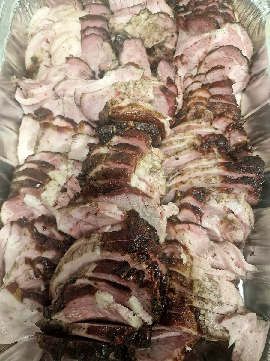 A large metal tray filled with perfectly sliced, roasted pork, ready for serving