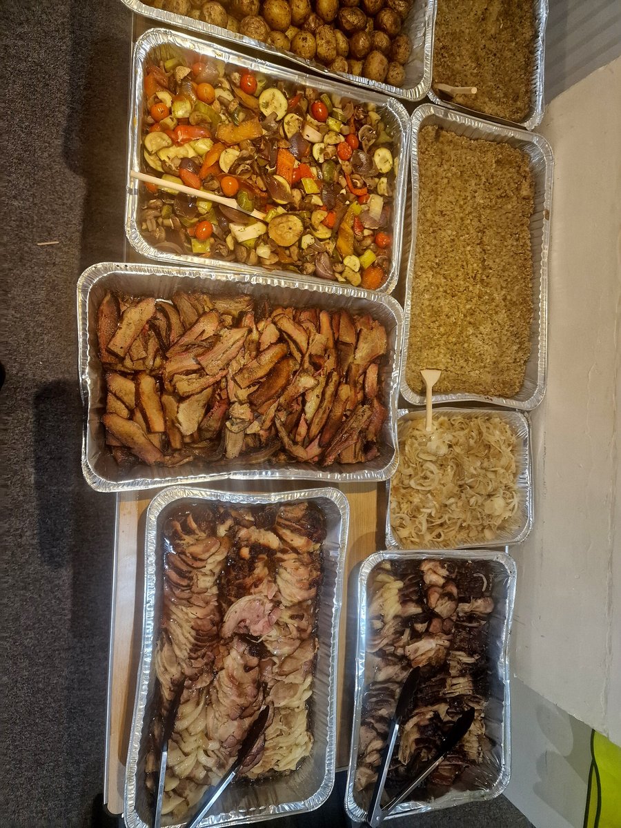 Trays of sliced meats, roasted vegetables, potatoes, and sides arranged for catering
