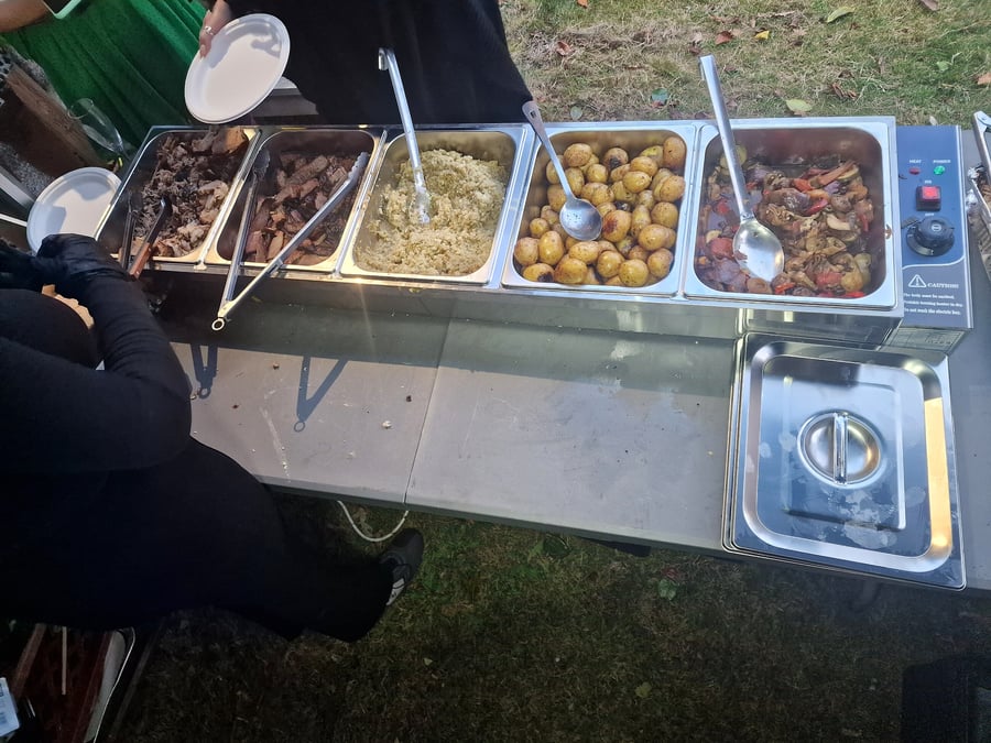 A buffet spread of various dishes including meat, potatoes, and vegetables is ready to serve