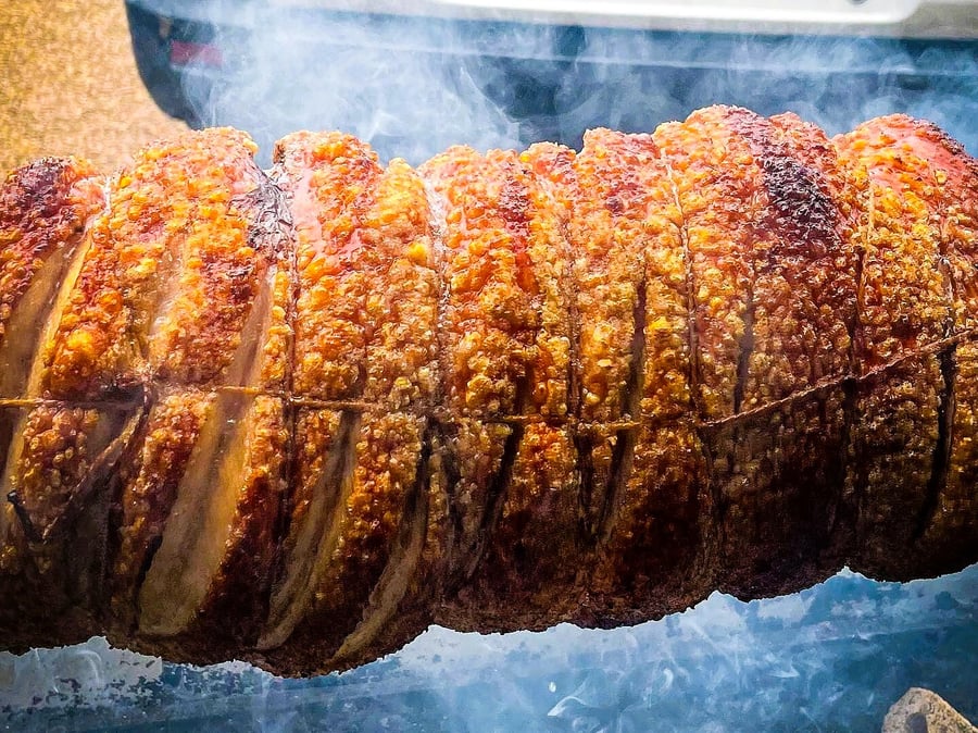A perfectly roasted hog with crispy crackling, slowly turning and smoking