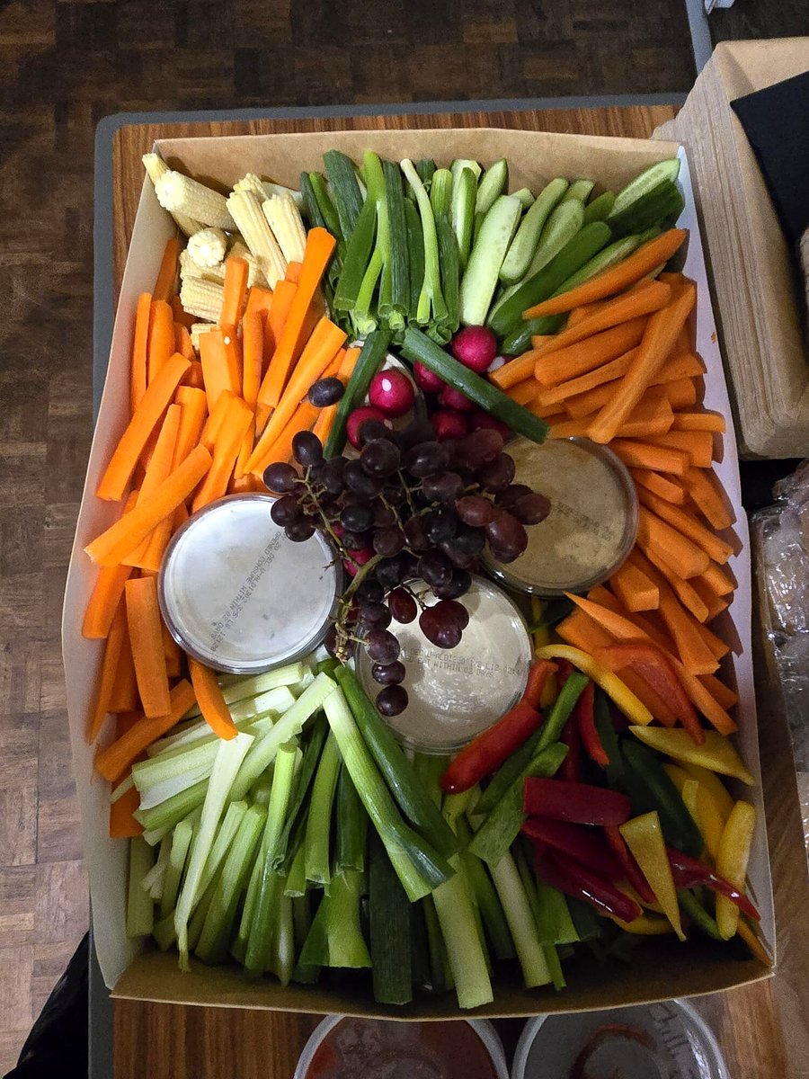 A large platter of fresh crudités with dips and grapes, ready for serving