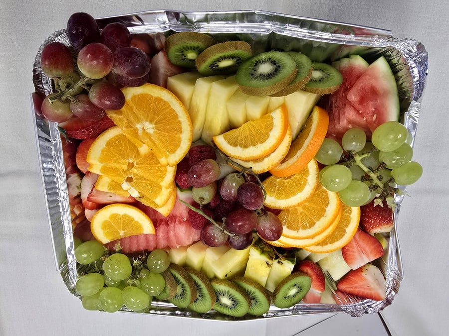 A vibrant fruit platter featuring a variety of fresh fruits in a foil tray