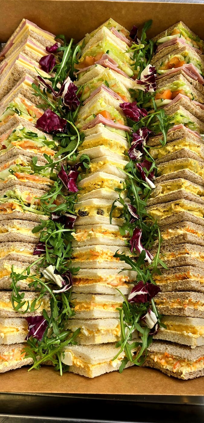 A beautifully arranged platter of assorted finger sandwiches with fresh garnishes