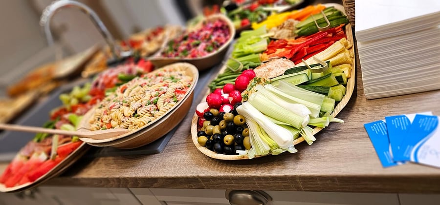 A selection of fresh salads and crudités are beautifully presented on a wooden counter