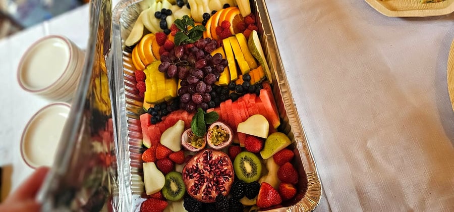 A large, foil platter overflowing with a vibrant assortment of fresh, cut fruits