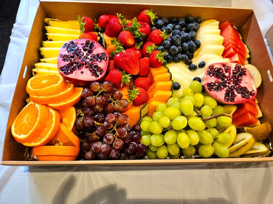 A large catering platter overflowing with a vibrant assortment of fresh, colourful fruits