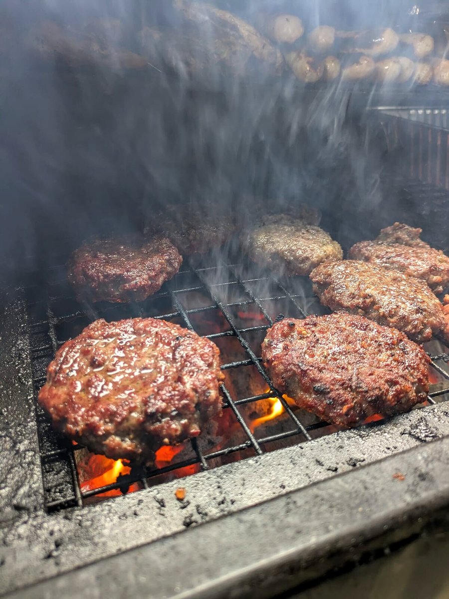Juicy burgers sizzling on a hot grill with visible smoke and flames (2)