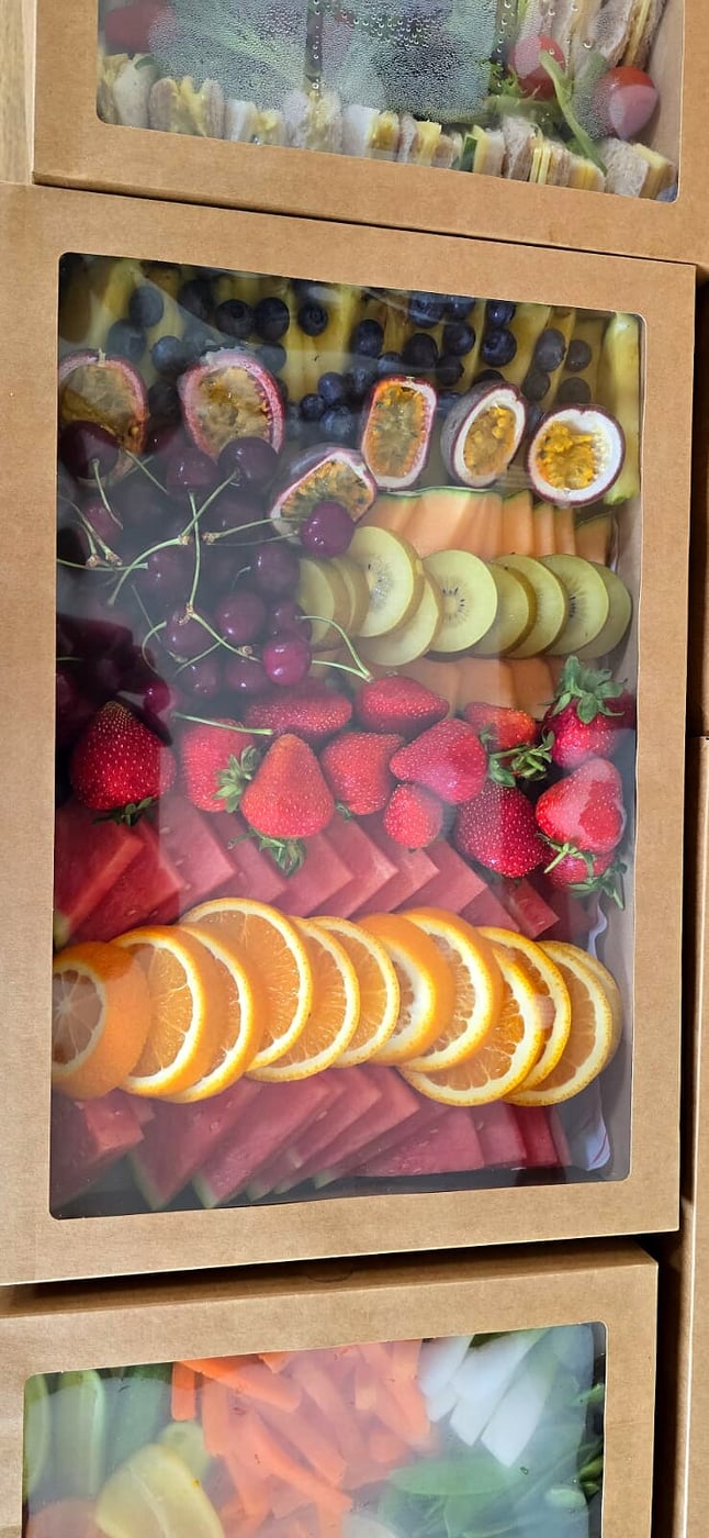 A beautifully arranged fruit platter in a catering box, ready for an event
