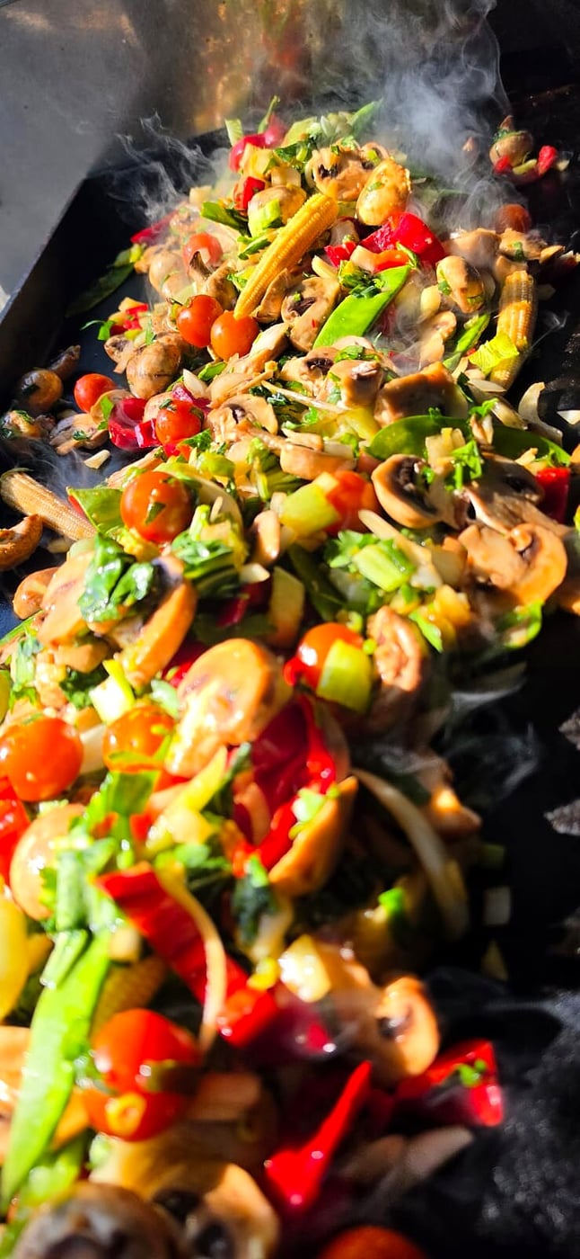 Fresh vegetables sizzling on a grill with visible smoke and steam