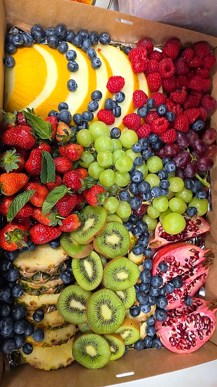 A vibrant platter overflowing with fresh fruits including berries, melon, kiwi, and pomegranate