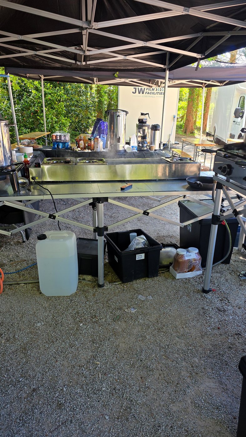 Outdoor catering setup on a film set with cooking equipment and supplies